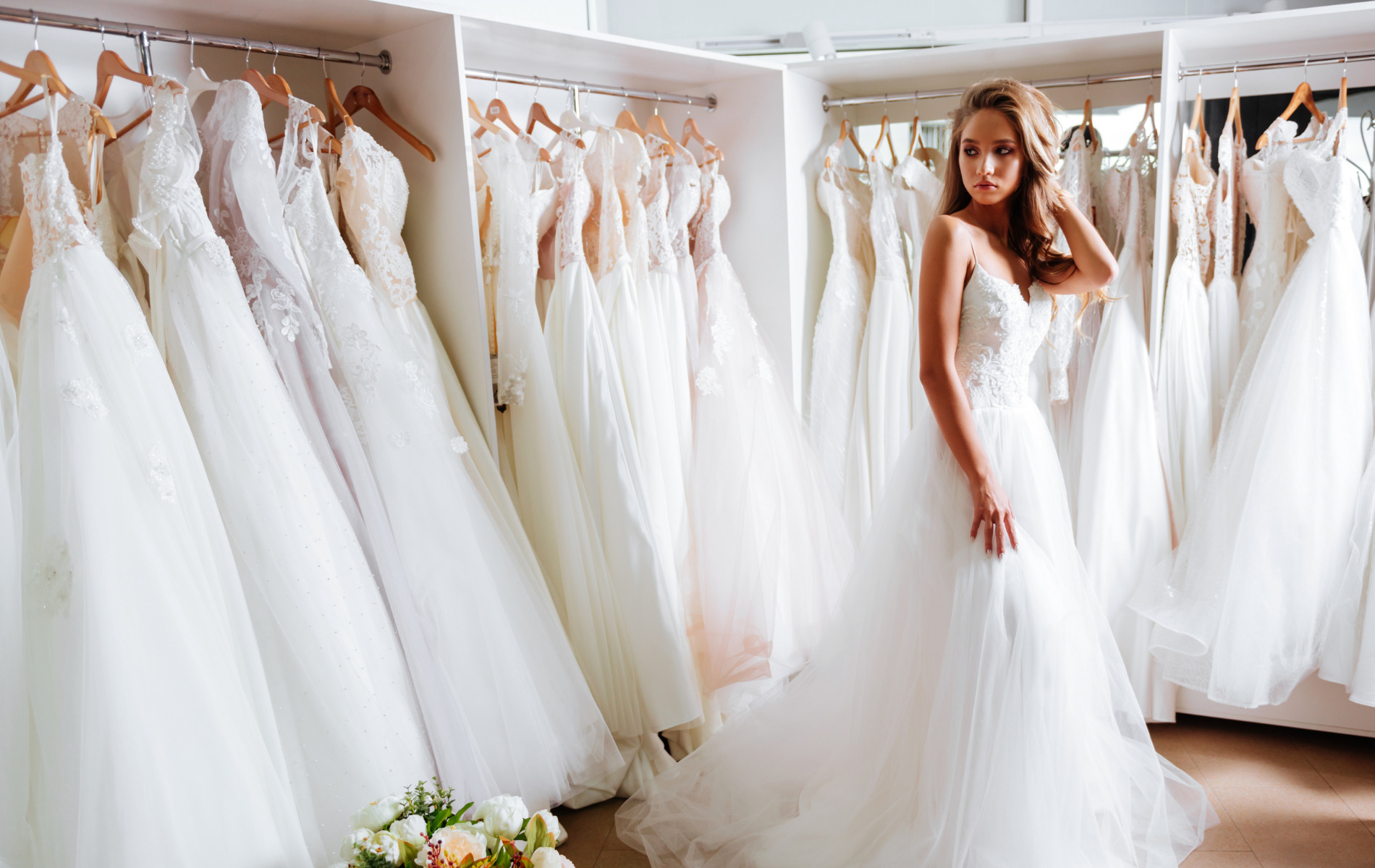 woman in bridal dress posing in a room full of other bridal dresses